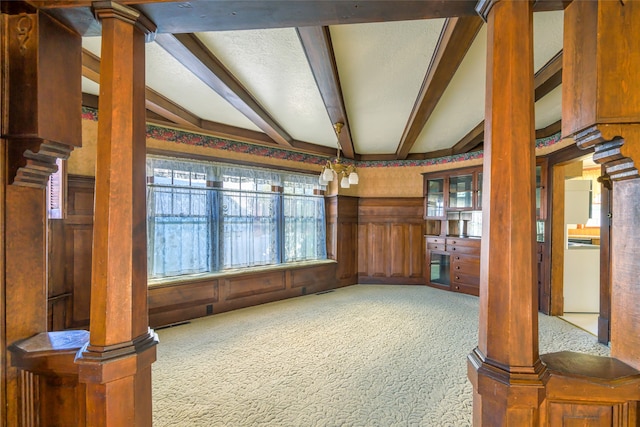 dining space featuring beamed ceiling, carpet flooring, and decorative columns