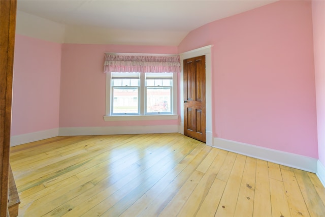 unfurnished room featuring lofted ceiling and light wood-type flooring