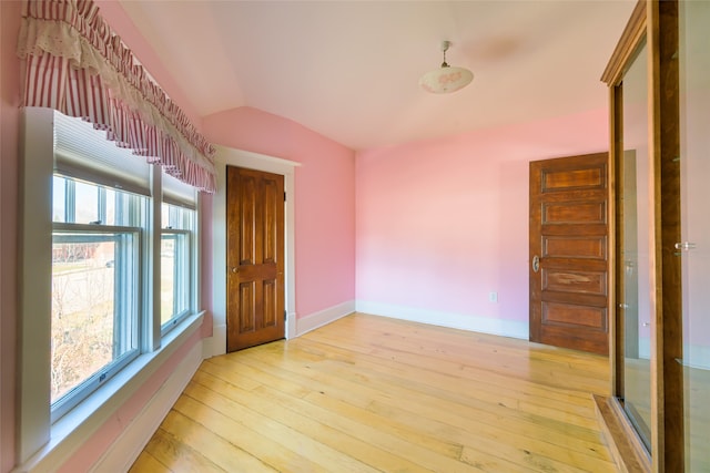 empty room with light hardwood / wood-style flooring and lofted ceiling