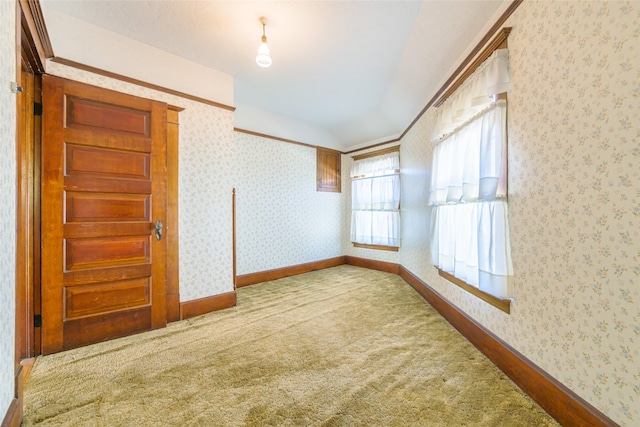 spare room featuring carpet flooring, ornamental molding, and vaulted ceiling