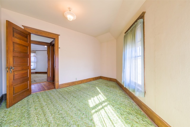 empty room with hardwood / wood-style flooring and vaulted ceiling