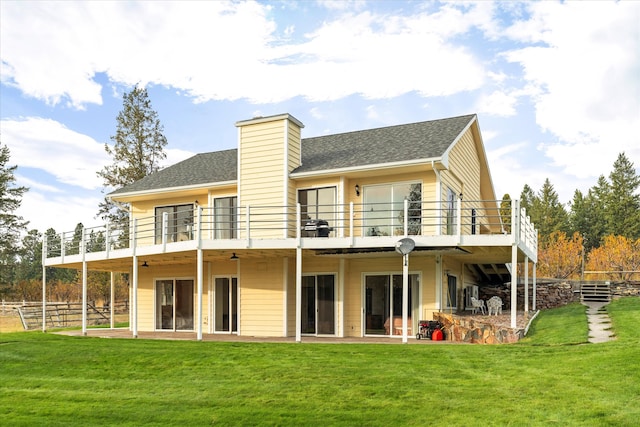 rear view of property featuring a balcony and a yard