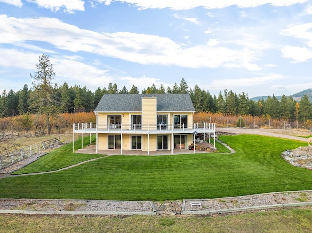 back of property featuring a wooden deck, a yard, and a patio