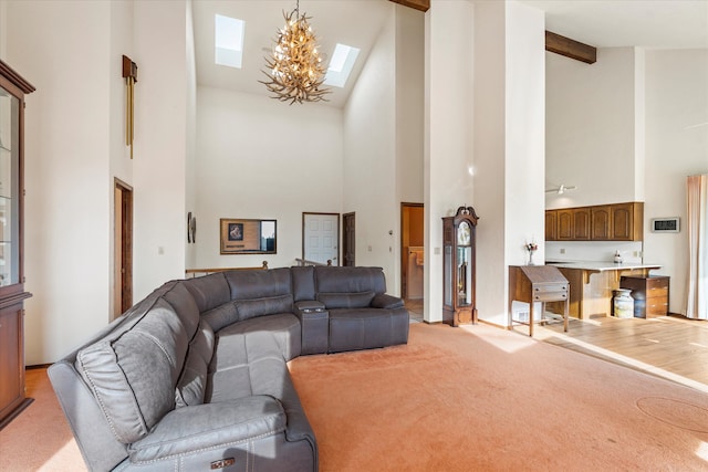 living room featuring a skylight, an inviting chandelier, light hardwood / wood-style flooring, high vaulted ceiling, and beamed ceiling