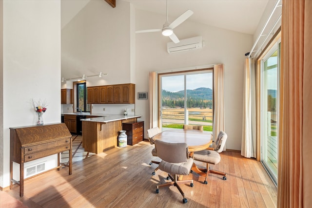 dining space featuring high vaulted ceiling, a mountain view, a wall unit AC, and light hardwood / wood-style flooring