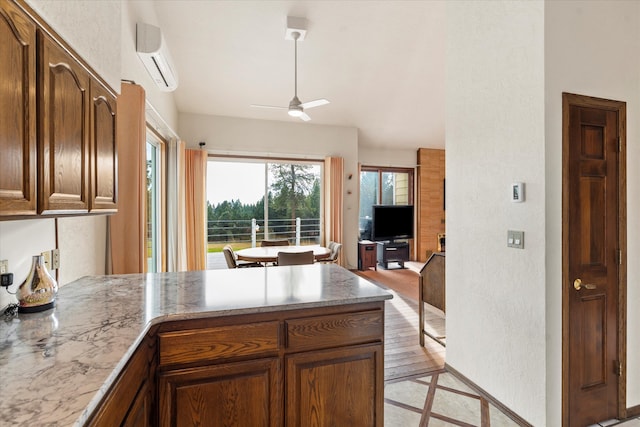 kitchen featuring ceiling fan, light hardwood / wood-style floors, an AC wall unit, and kitchen peninsula