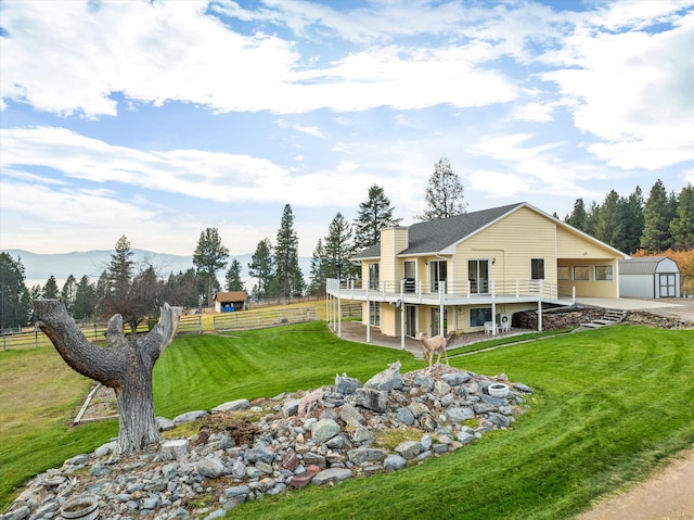 rear view of property with a yard, a deck with mountain view, and a shed