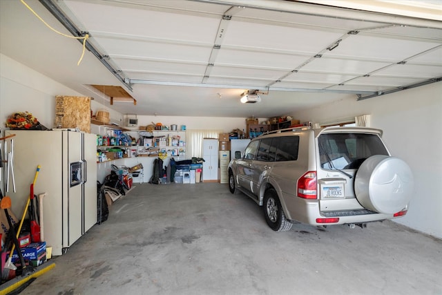 garage featuring white fridge with ice dispenser and a garage door opener