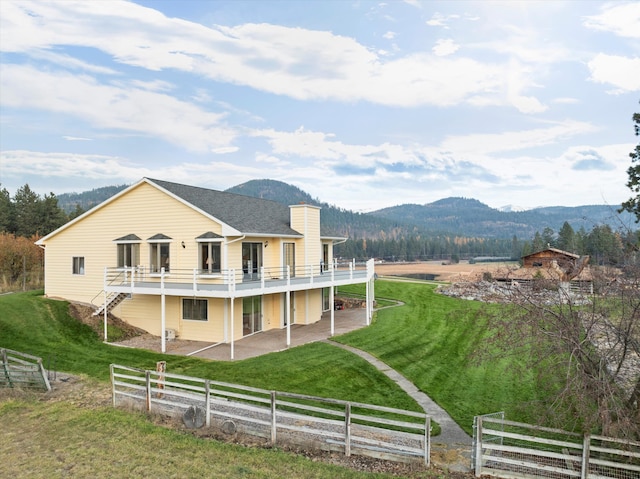 rear view of house featuring a deck with mountain view, a yard, a rural view, and a patio