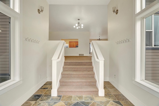 staircase with a notable chandelier and plenty of natural light