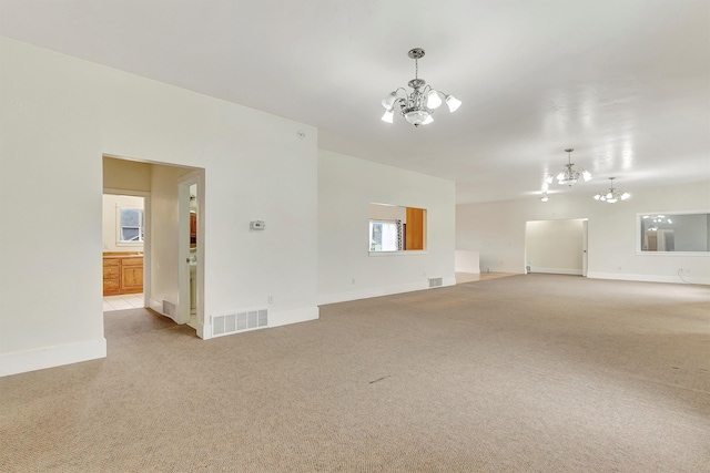 carpeted spare room with an inviting chandelier