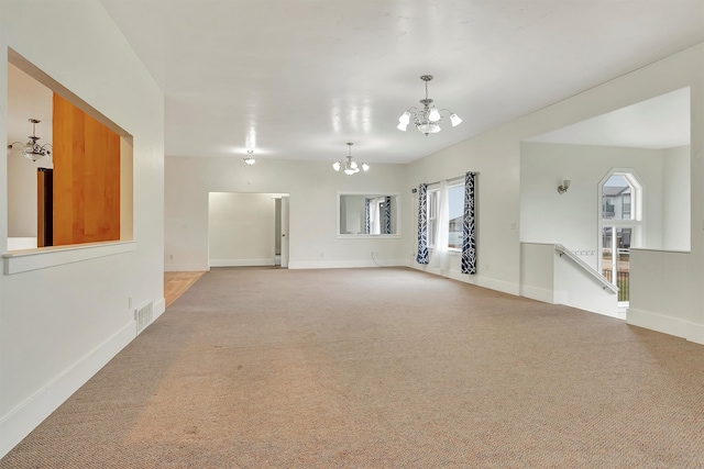 carpeted spare room featuring a chandelier