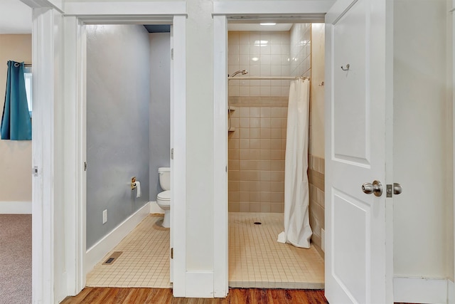 bathroom featuring walk in shower, toilet, and hardwood / wood-style flooring