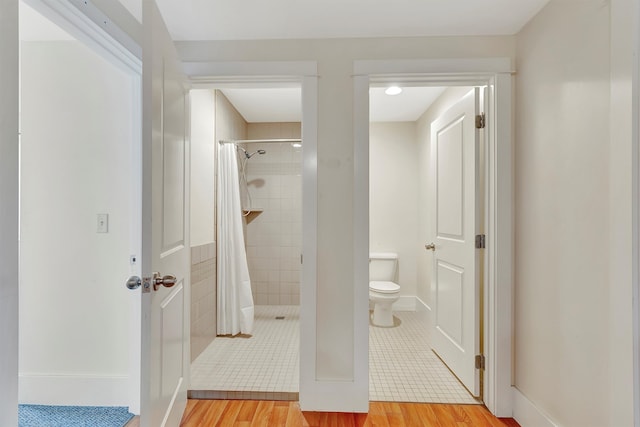 bathroom with hardwood / wood-style flooring, toilet, and walk in shower