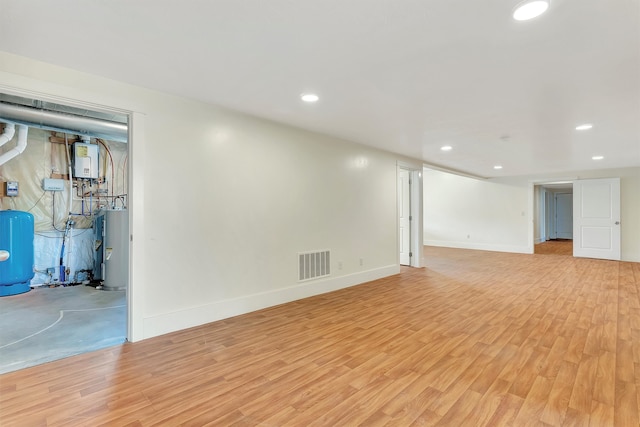 basement featuring light hardwood / wood-style floors and electric water heater