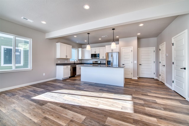 kitchen with a kitchen island, sink, white cabinets, hanging light fixtures, and stainless steel appliances