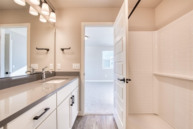 bathroom with hardwood / wood-style flooring, vanity, and walk in shower