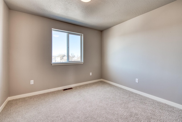 carpeted empty room featuring a textured ceiling