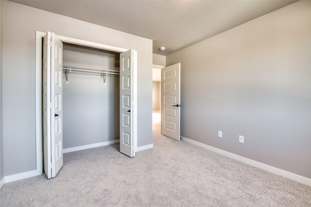 unfurnished bedroom with light colored carpet, a closet, and a textured ceiling