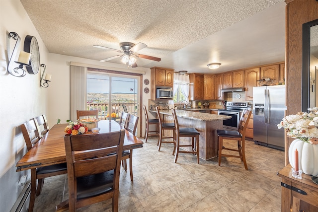 dining space featuring ceiling fan, sink, and a textured ceiling