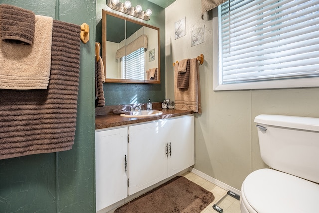 bathroom featuring tile patterned flooring, vanity, a healthy amount of sunlight, and toilet