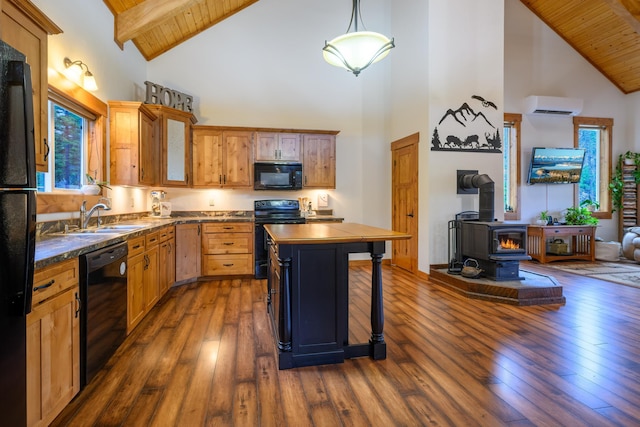 kitchen with a wood stove, dark wood-type flooring, high vaulted ceiling, black appliances, and decorative light fixtures