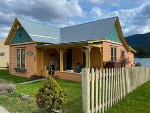 back of property featuring fence, metal roof, and a yard