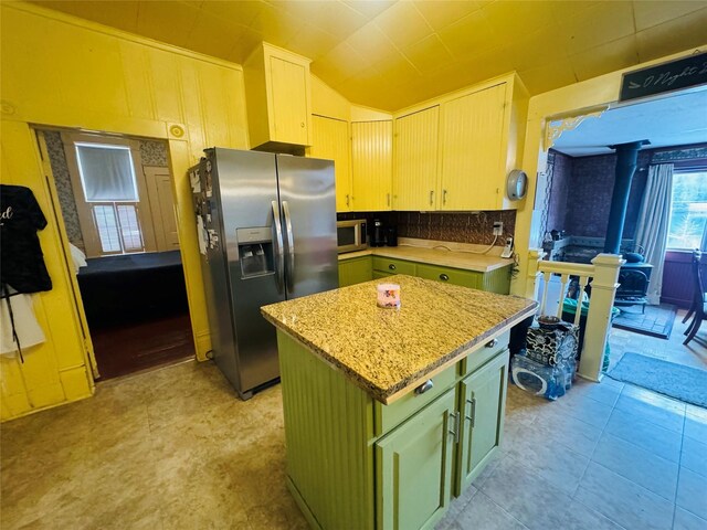 dining area featuring a wainscoted wall, a wood stove, and wallpapered walls