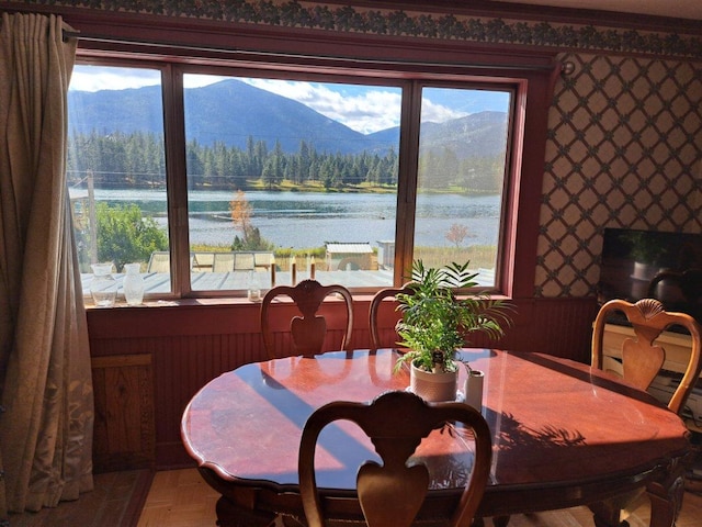 dining area with parquet floors, a healthy amount of sunlight, and a water and mountain view