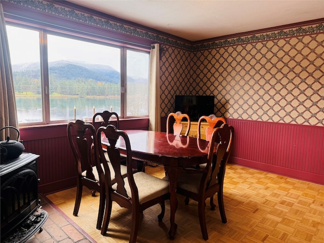 dining room with a water view, crown molding, and light parquet floors