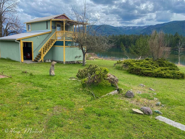 view of yard with a deck with water view and stairs