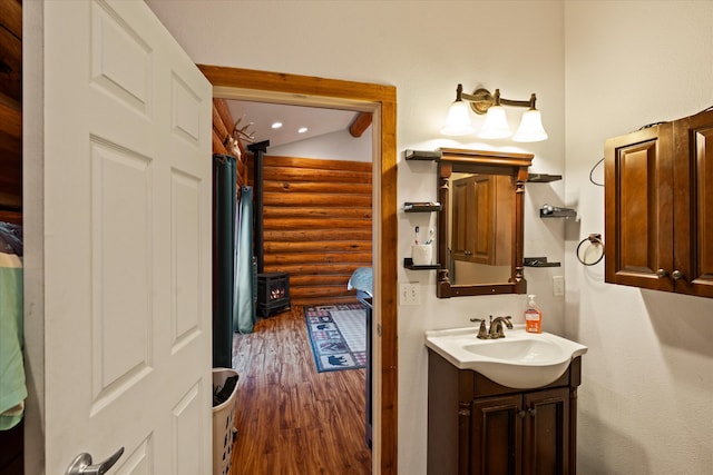 bathroom with a wood stove, vanity, and hardwood / wood-style flooring