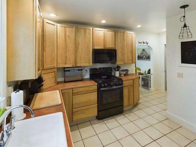 kitchen featuring hanging light fixtures, light tile patterned floors, black appliances, and sink