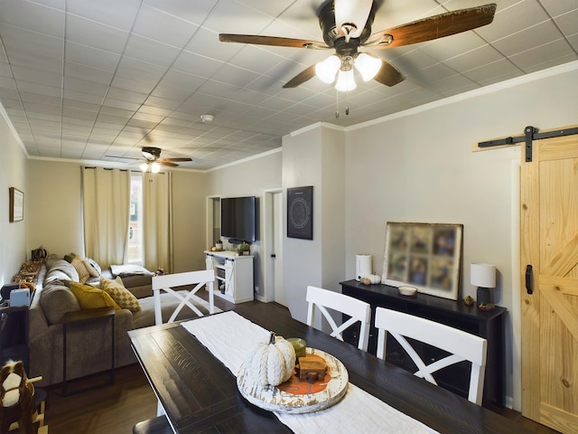 dining room with a barn door, dark hardwood / wood-style flooring, and crown molding