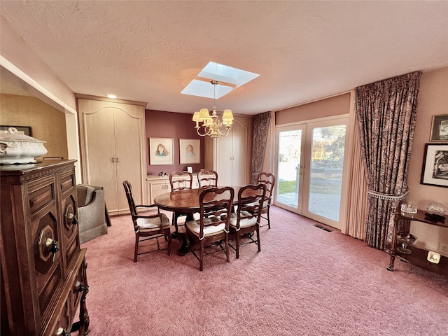 carpeted dining space featuring a notable chandelier, a textured ceiling, and a skylight