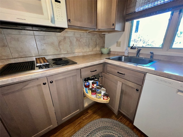 kitchen with dark hardwood / wood-style flooring, white appliances, backsplash, and sink