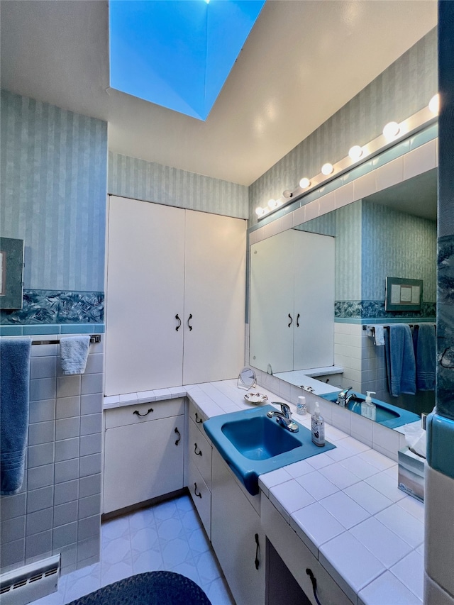 bathroom with vanity, baseboard heating, and tile walls