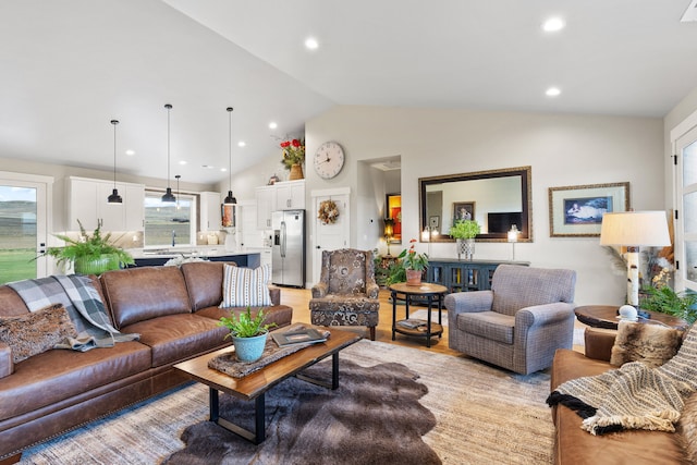 living room with light hardwood / wood-style floors, sink, and high vaulted ceiling