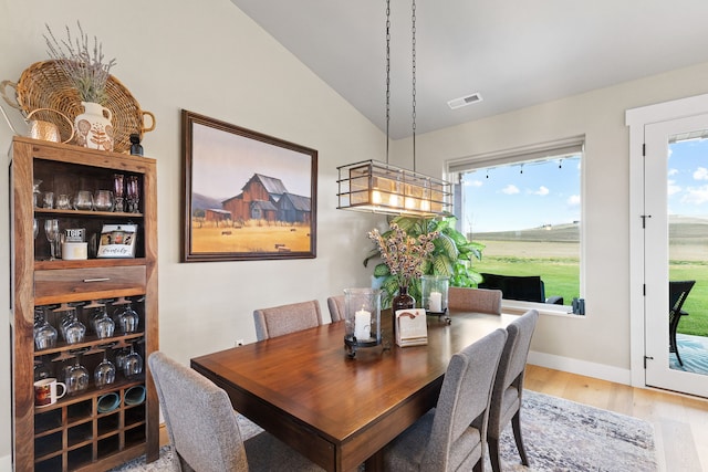 dining room featuring a healthy amount of sunlight, vaulted ceiling, and wood-type flooring