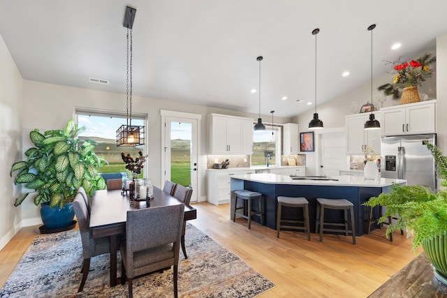 dining area featuring sink, high vaulted ceiling, and light hardwood / wood-style floors