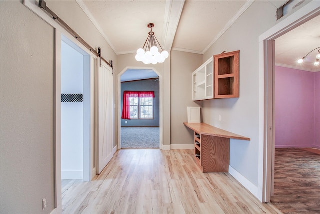 hallway featuring a barn door, light wood-type flooring, a chandelier, and ornamental molding