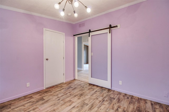 unfurnished bedroom with crown molding, a barn door, and light hardwood / wood-style floors