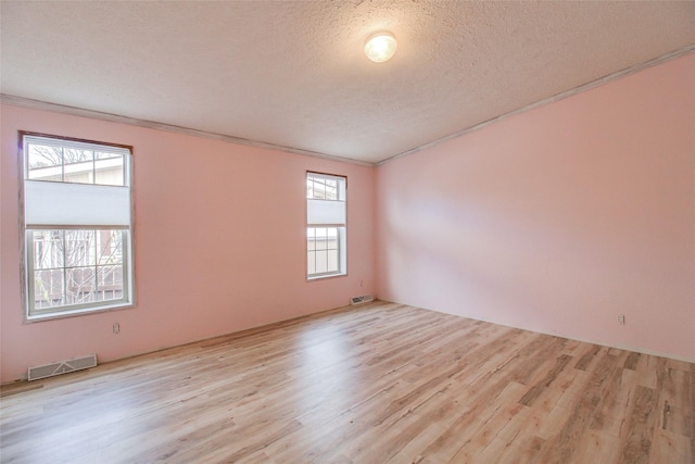 empty room featuring ornamental molding, a textured ceiling, and light hardwood / wood-style flooring