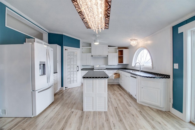 kitchen featuring a notable chandelier, a kitchen island, sink, white cabinetry, and fridge with ice dispenser