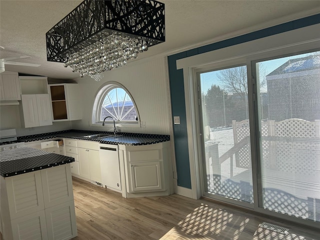 kitchen with light hardwood / wood-style floors, white dishwasher, a textured ceiling, white cabinets, and sink