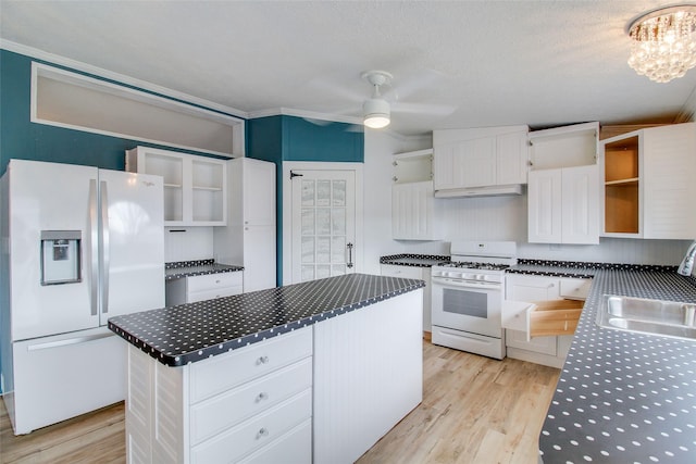 kitchen with white appliances, a center island, white cabinetry, light hardwood / wood-style floors, and sink