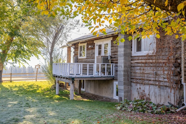 rear view of property featuring a yard and a wooden deck