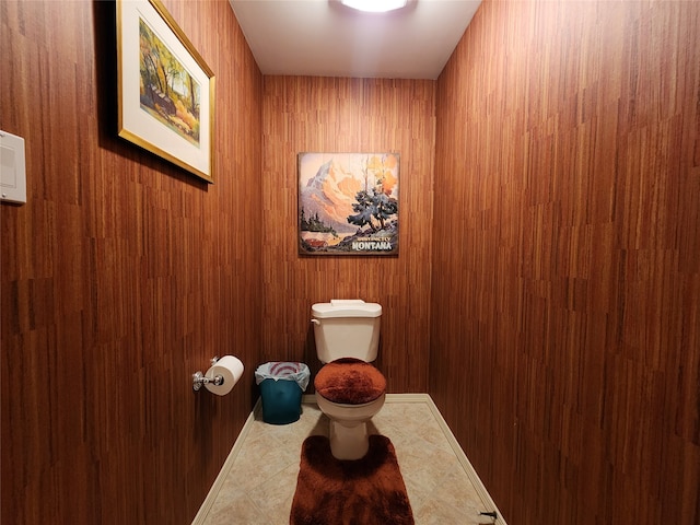 bathroom with tile patterned floors, wood walls, and toilet