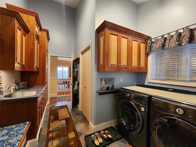 clothes washing area with washing machine and clothes dryer, sink, and cabinets