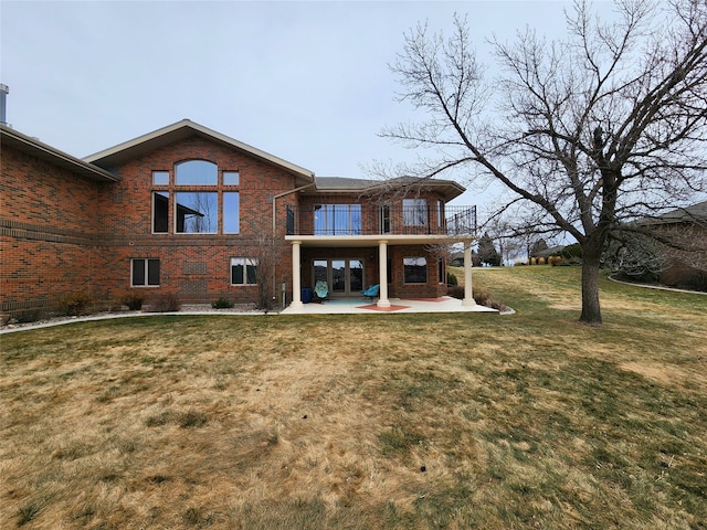 rear view of house with a yard, a balcony, and a patio